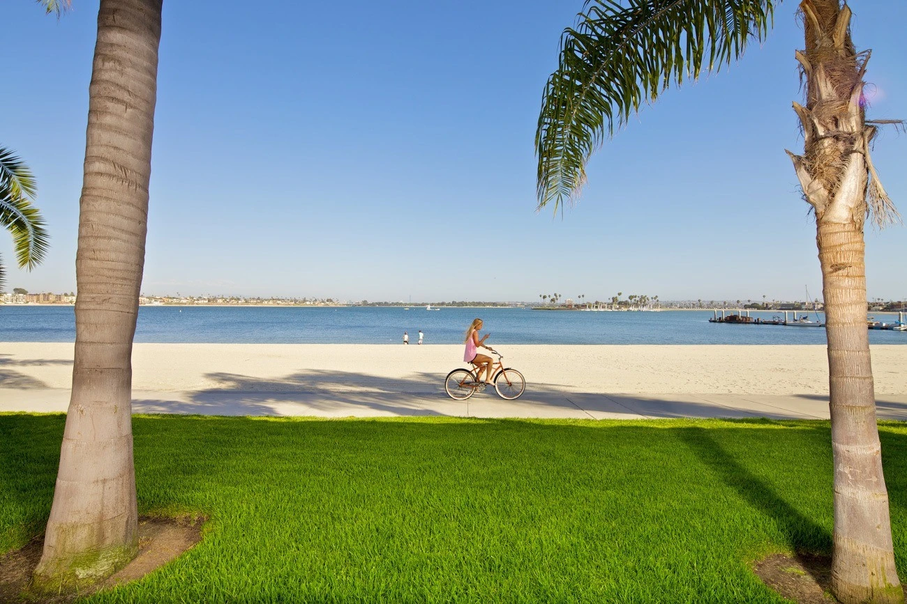 A girl rides a bike around Mission Bay on the trail that passes by Mission Bay hotels.