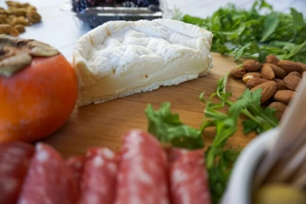 When you make a charcuterie and cheese platter, cut large cheeses in half so guests have easier access to them.