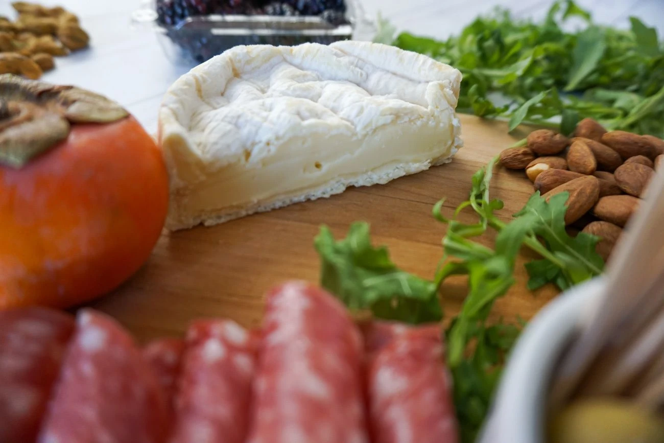 When you make a charcuterie and cheese platter, cut large cheeses in half so guests have easier access to them.