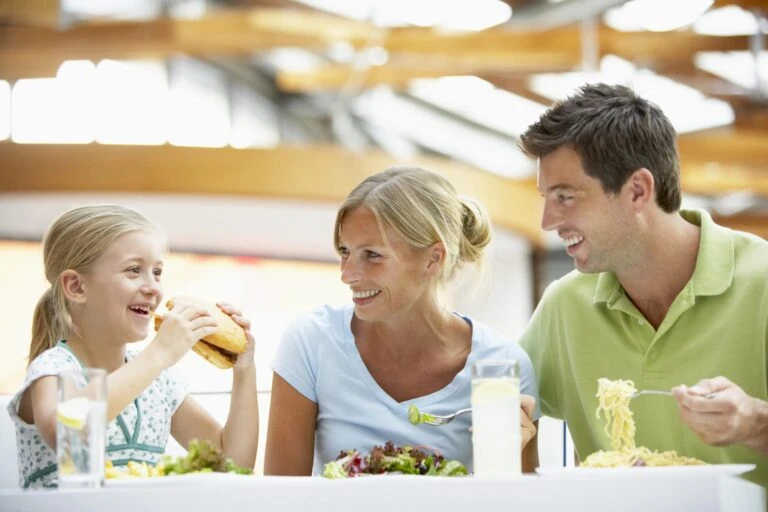 A family of two adults and a little eat lunch together.