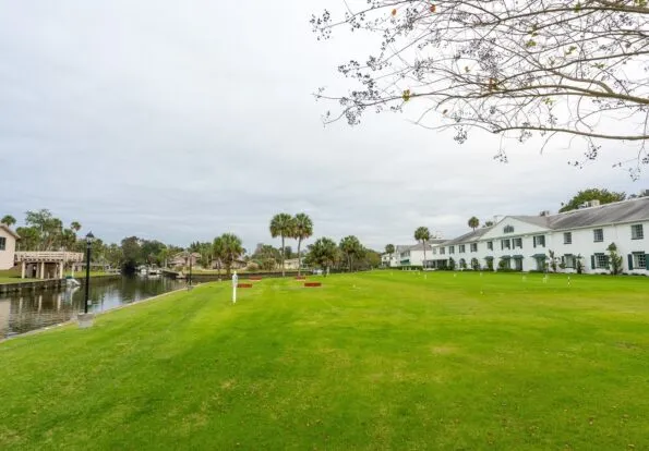 Large grassy area bordering the river and some guest rooms.