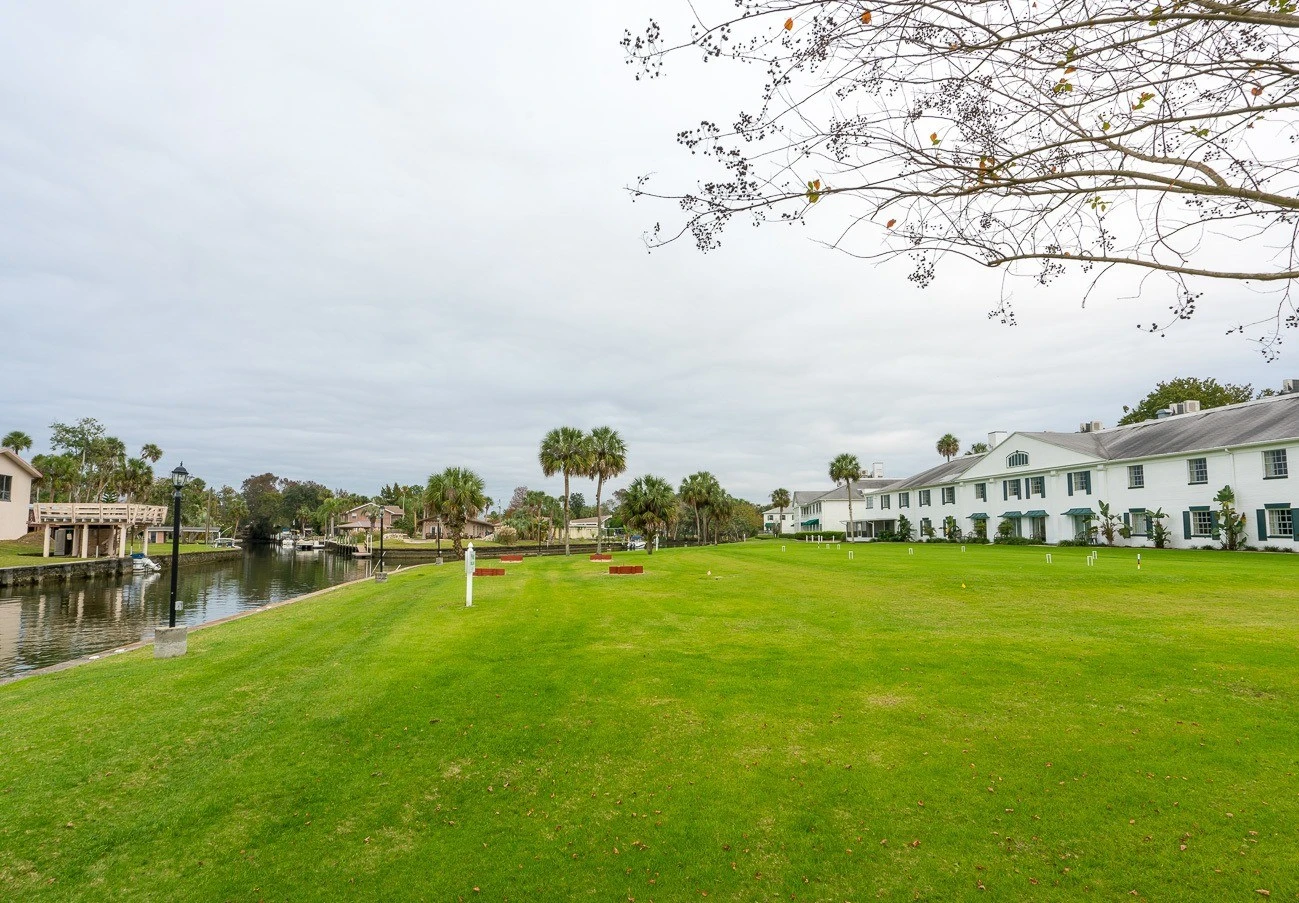 Large grassy area bordering the river and some guest rooms.
