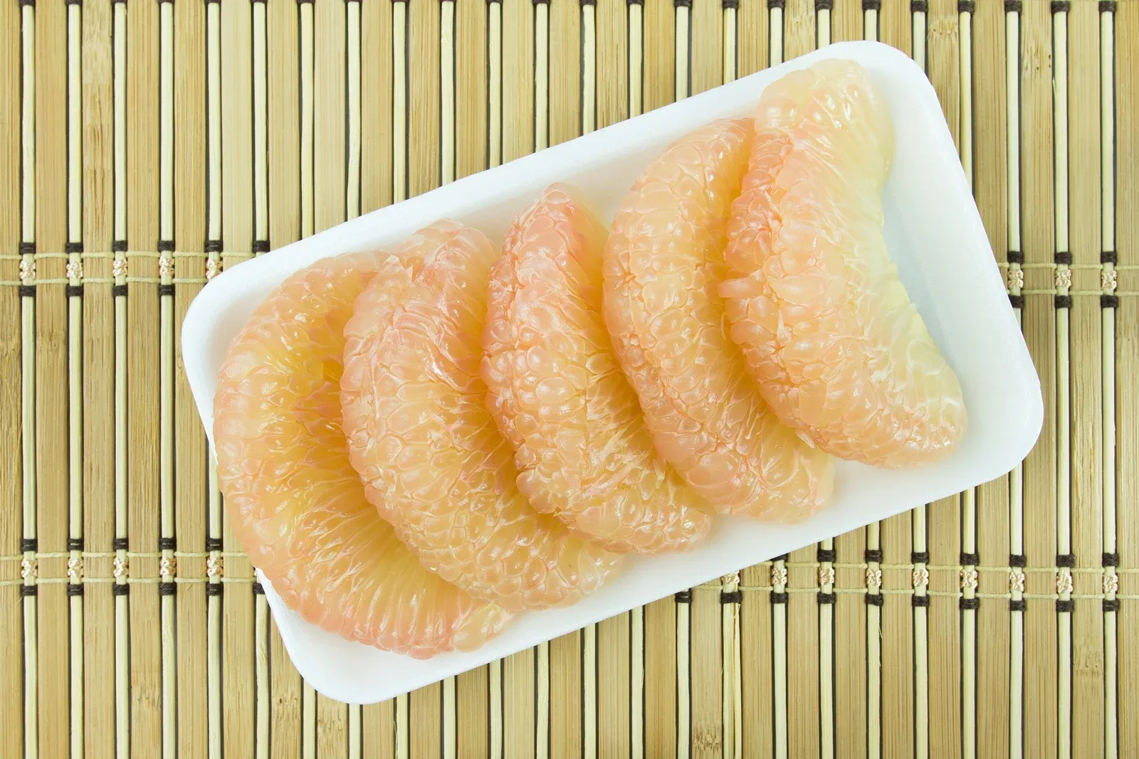 Peeled pomelo on a tray just as they sell it in the grocery store.
