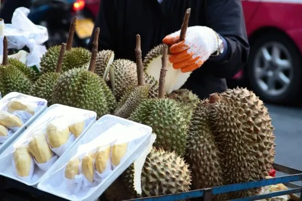 A street vendor sells whole and cut durian, one of the weirdest Asian fruits.