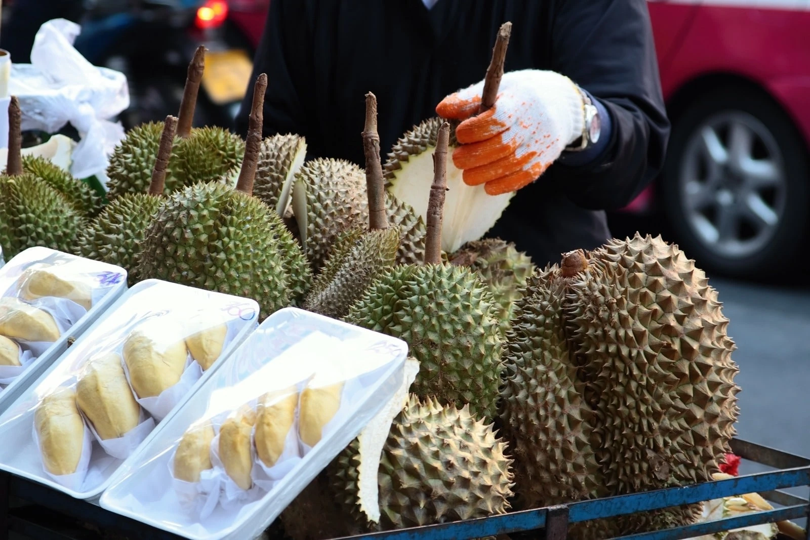 A street vendor sells whole and cut durian, one of the weirdest Asian fruits.