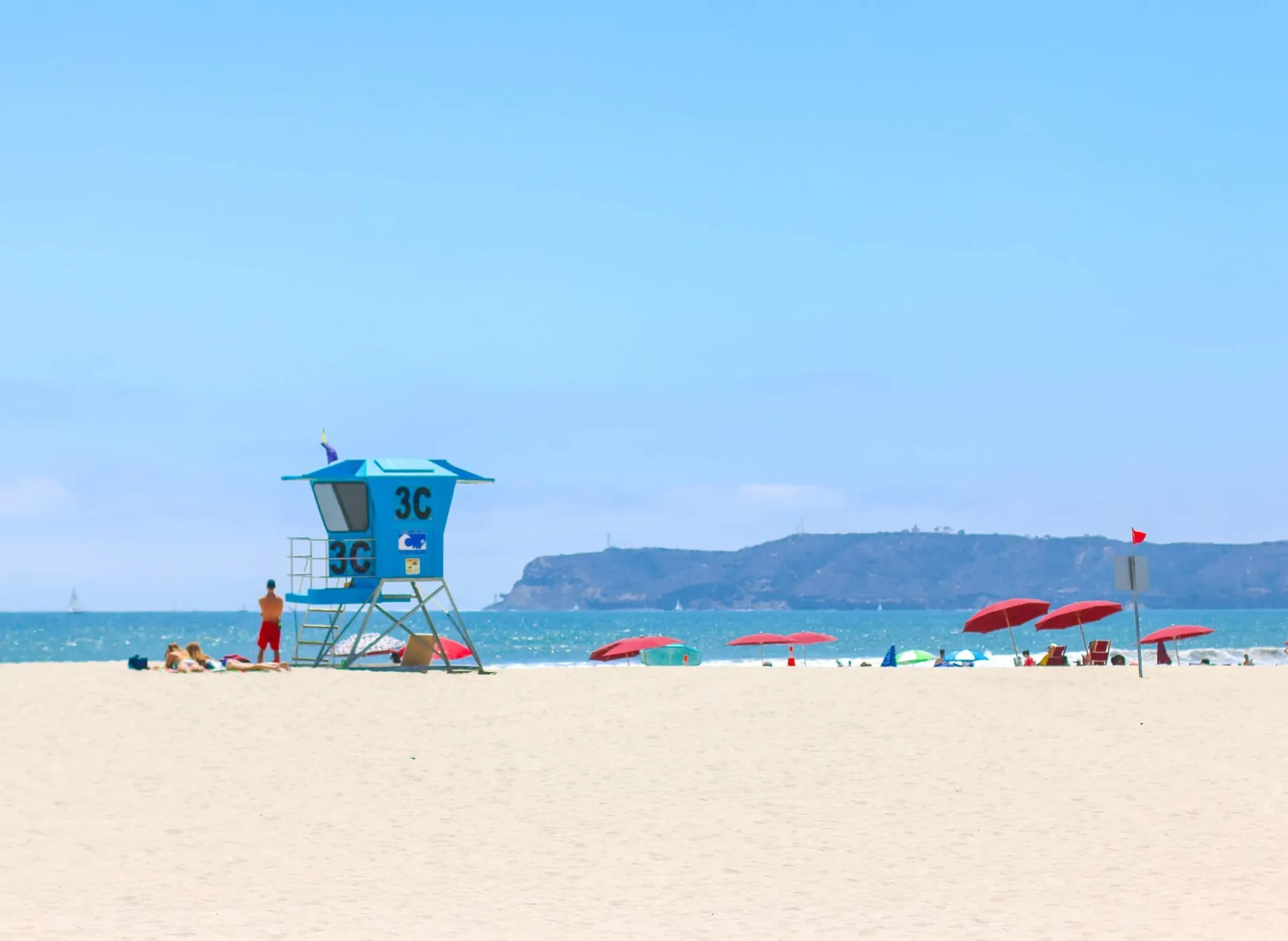 A lifeguard looks over the Pacific Ocean on a sunny day at Coronado Central Beach, a popular beach that families love.