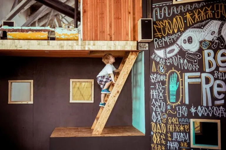 A toddler boy climbs up a ladder at The New Children's Museum in San Diego.