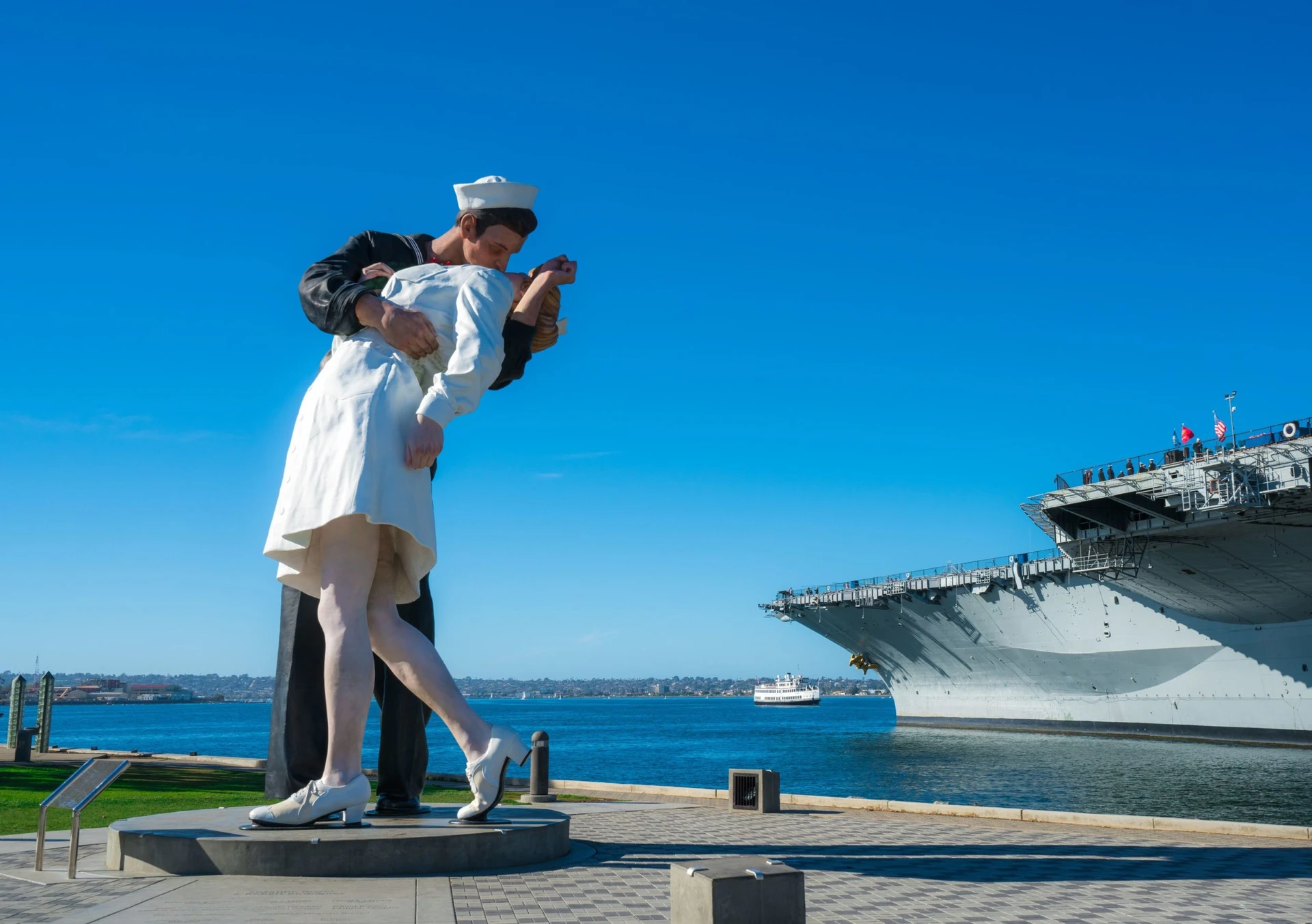The Unconditional Surrender kissing statue with the USS Midway and San Diego Bay in the background.