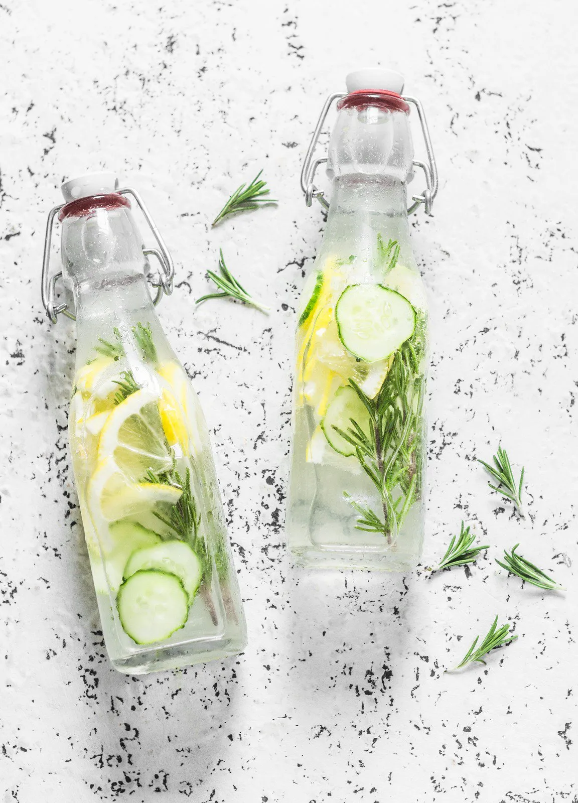 Two bottles of infused water with lemon, cucumber and rosemary.