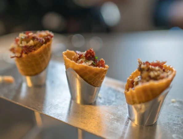 Three bacon-filled cones made out of bacon fat in a silver display.