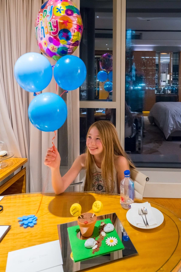 My daughter holds birthday balloons sent by the hotel.