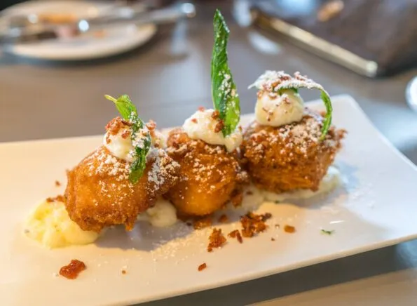 Bacon beignets with a dollop of sweet cream cheese and bacon crumbles.