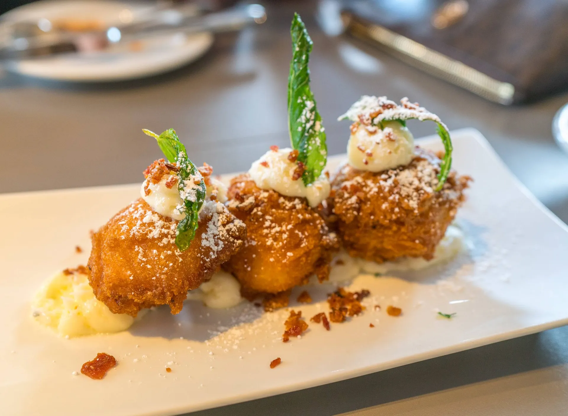 Bacon beignets with a dollop of sweet cream cheese and bacon crumbles.