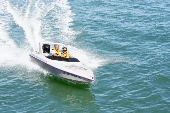 Two riders drive the mini speedboat in San Diego Bay.