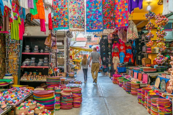 Brightly-colored blankets, hats, and ceramics line an aisle inside of La Ciudadela the best market to shop when in Mexico City with kids.