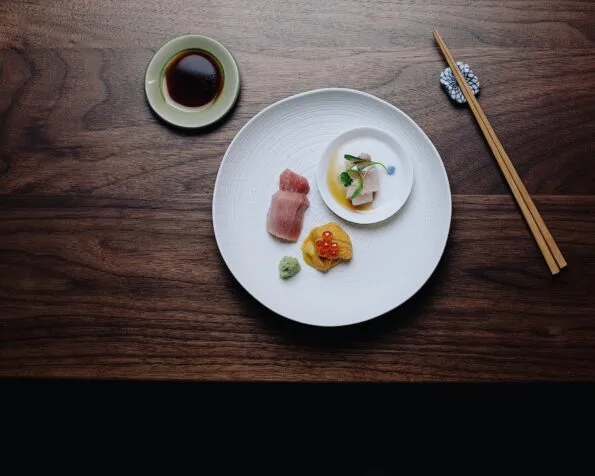 Delicate sashimi on a large white plate on a table at Himitsu. 