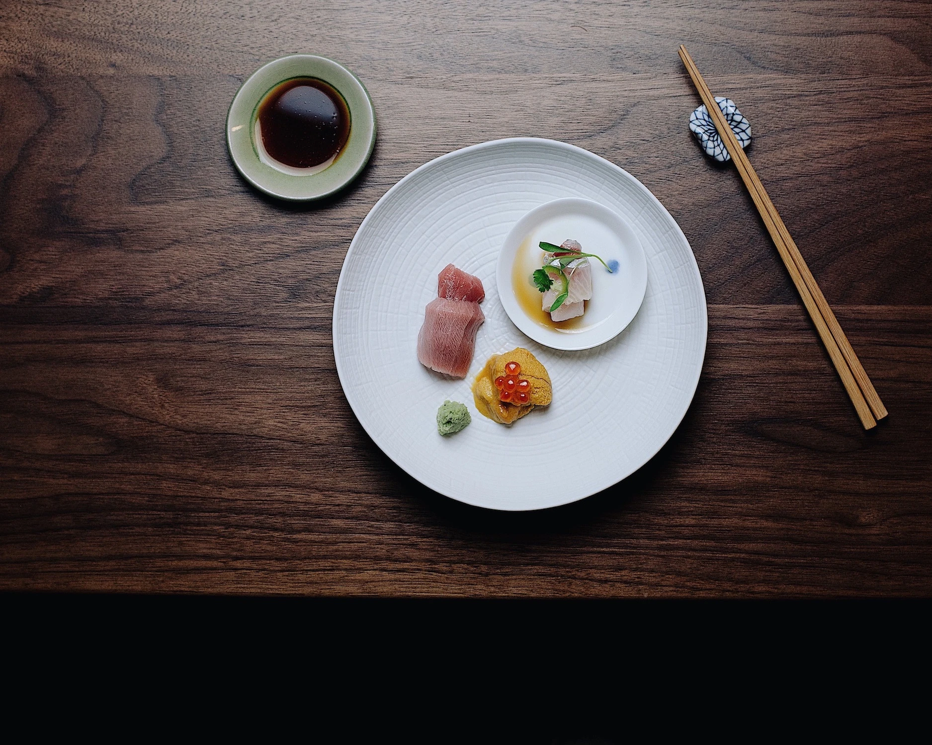 Delicate sashimi on a large white plate on a table at Himitsu. 