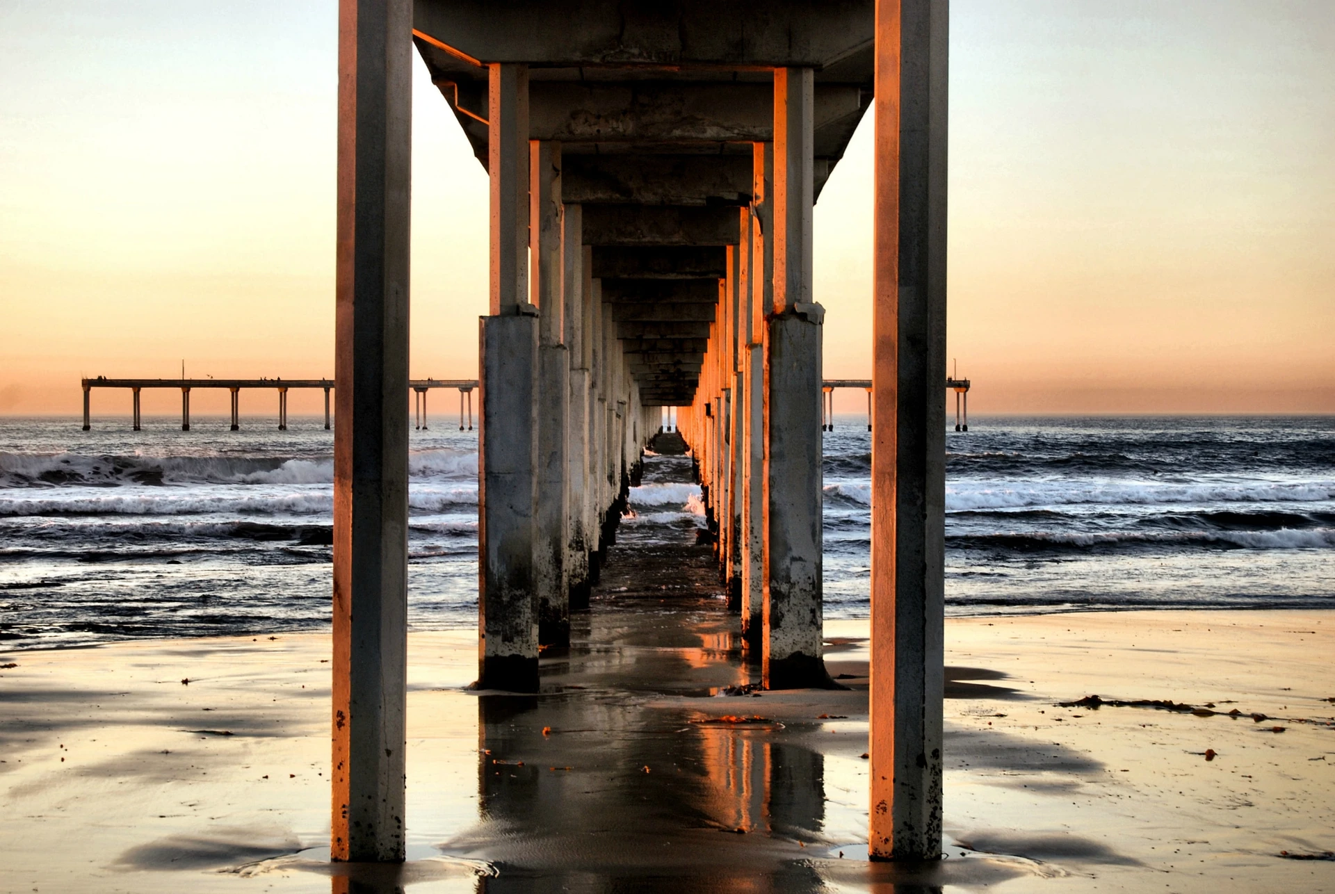 View of the sunset between the pylons of Ocean Beach pier.