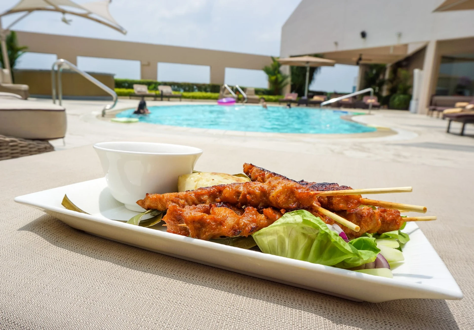 Satay on a plate by the pool at Four Seasons Singapore