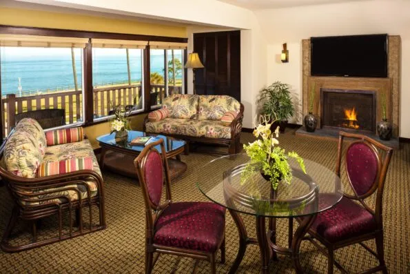 A living room in a suite at Pantai Inn with tropical themed furnishings and an ocean view.