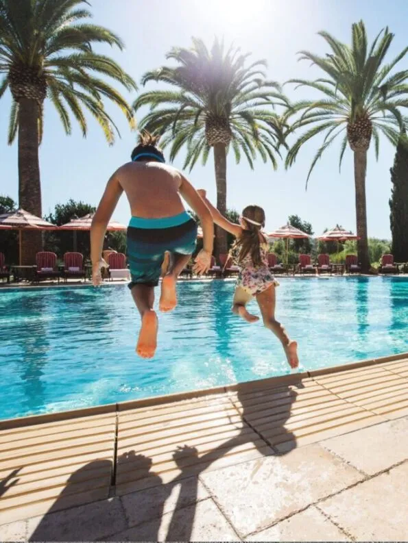 A father and daughter jump into the Main Pool at Fairmont Grand Del Mar.