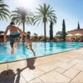 A father and daughter jump into the Main Pool at Fairmont Grand Del Mar.