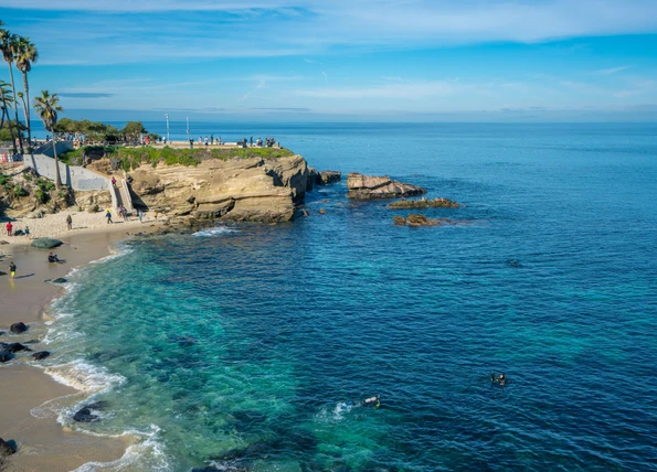 La Jolla Cove beach on a sunny day with scuba divers in the water.