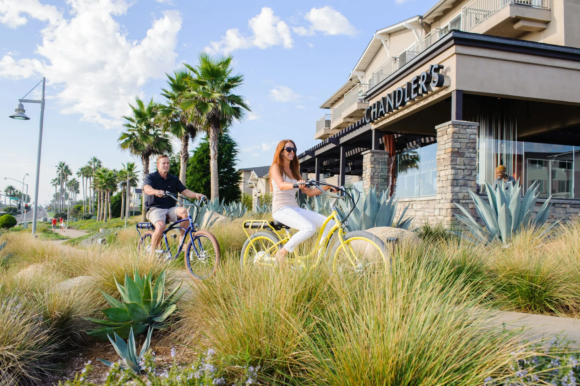 Two guests ride bikes in front of the resort.