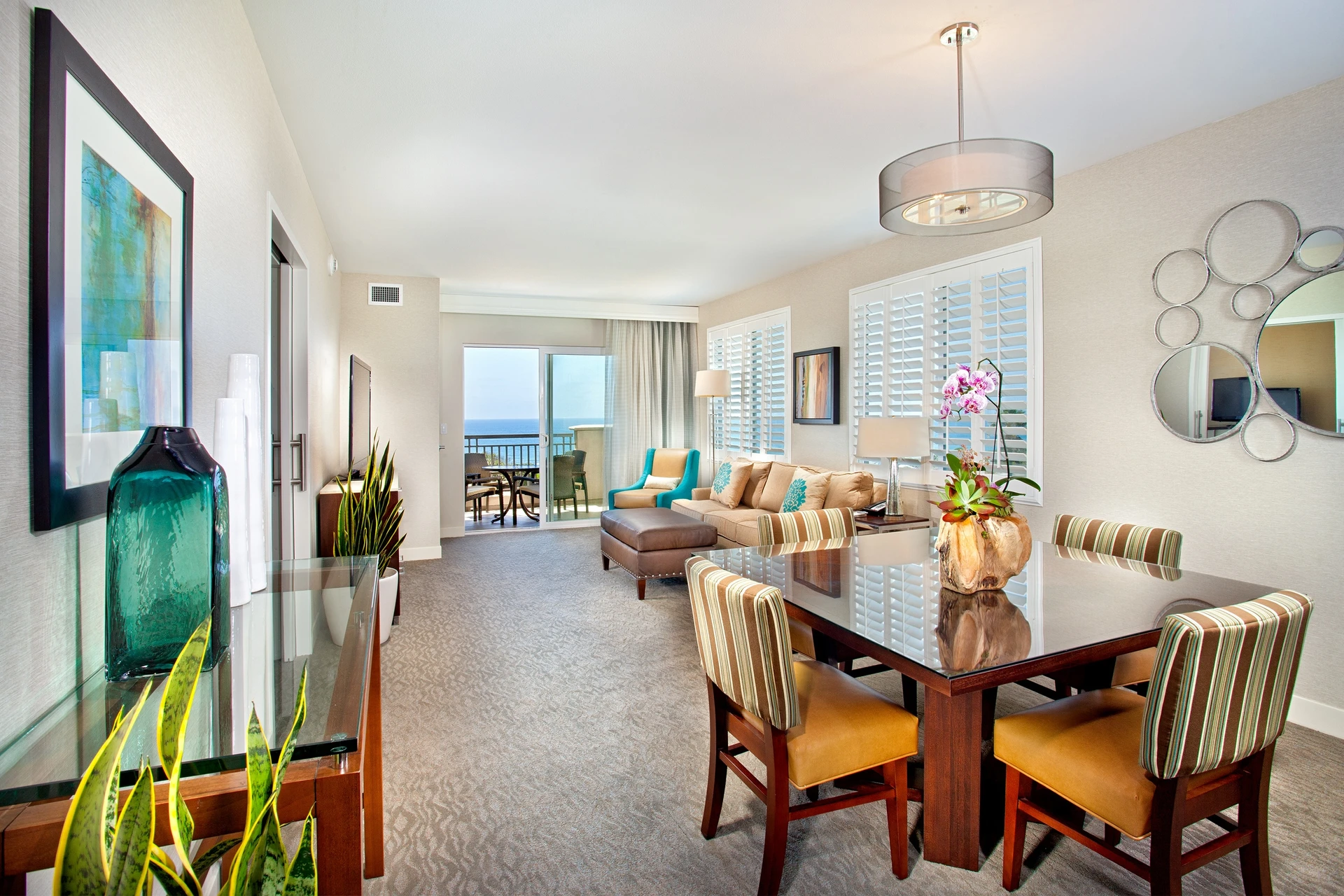 Interior of an ocean view suite looking over the dining table to the balcony.