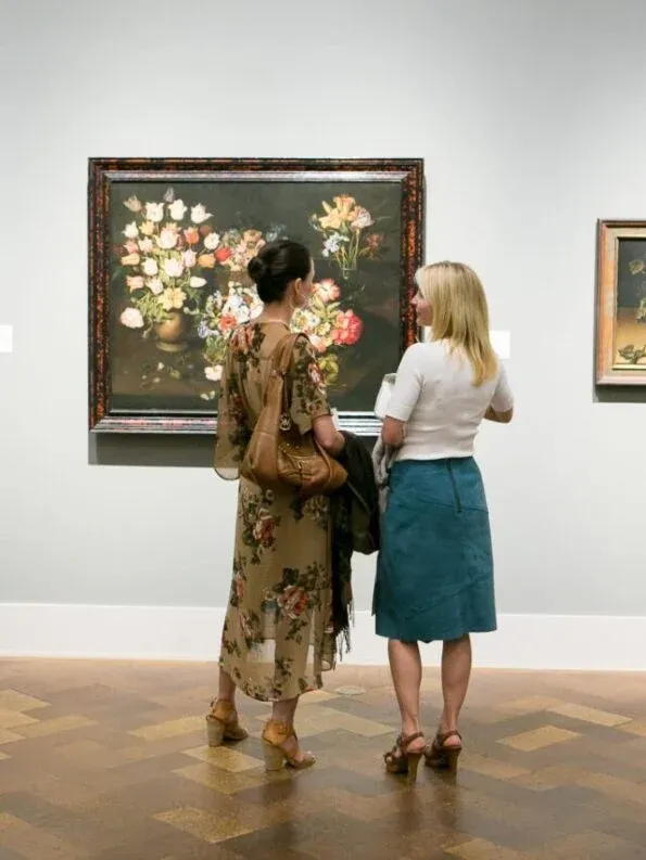 Two women stand in front of a painting at San Diego Museum of Art