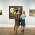 Two women stand in front of a painting at San Diego Museum of Art