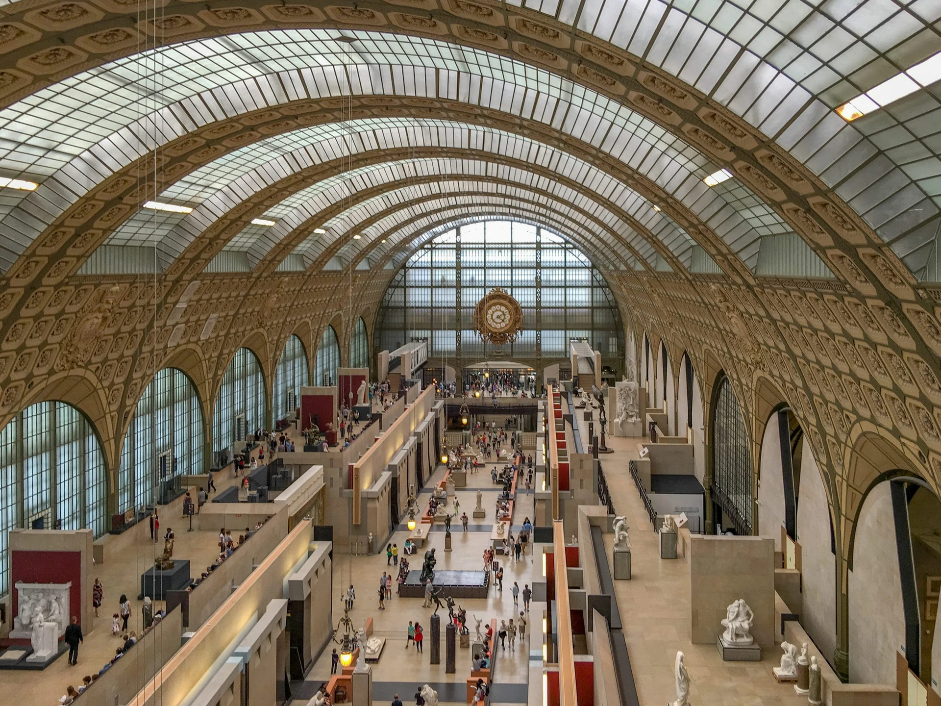 The grand interior of Musee d'Orsay with the famous clock in the background and arched ceilings.