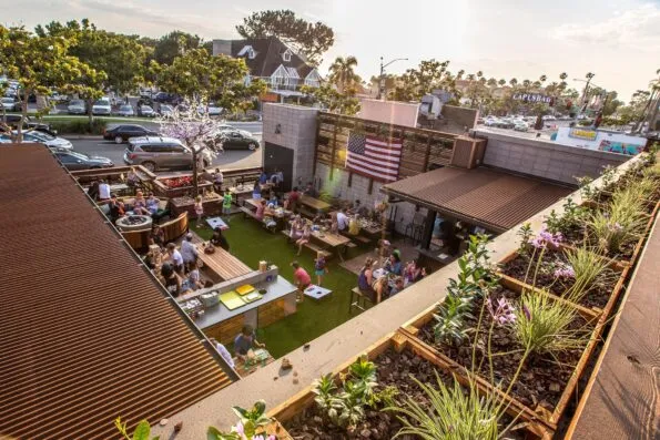Kids play corn hole while guests hang out at picnic tables at Park 101 in Carlsbad's Garden Pub area.