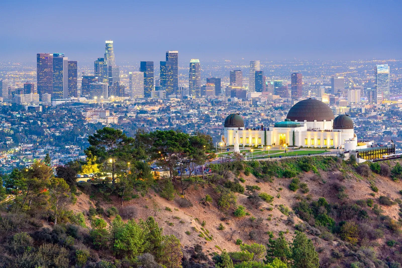 Aerial view of Griffith Park Observatory with city skyline in the background.