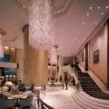 Guests walk through Island Shangri-La Hong Kong's ground floor area under large chandeliers.