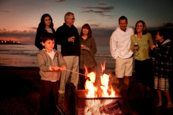 A family roasts s'mores at night on the beach at La Jolla Beach and Tennis Club