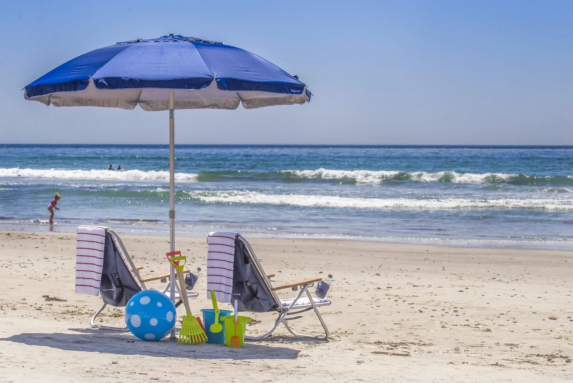 Two chairs, an umbrella and sand toys set up by The Grand Beach Service on Del Mar beach.