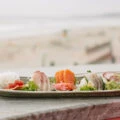 A plate of nigiri sushi on a ledge with Mission Beach in the background