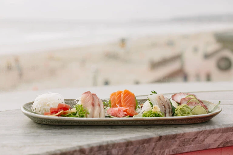 A plate of nigiri sushi on a ledge with Mission Beach in the background
