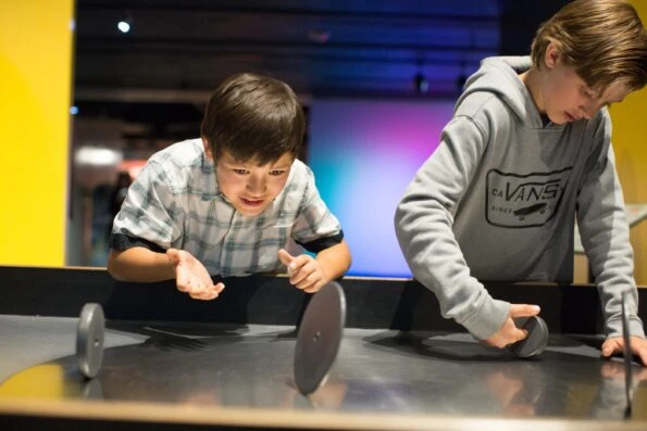 Two boys spin discs at a hands-on Fleet Science Center exhibit.
