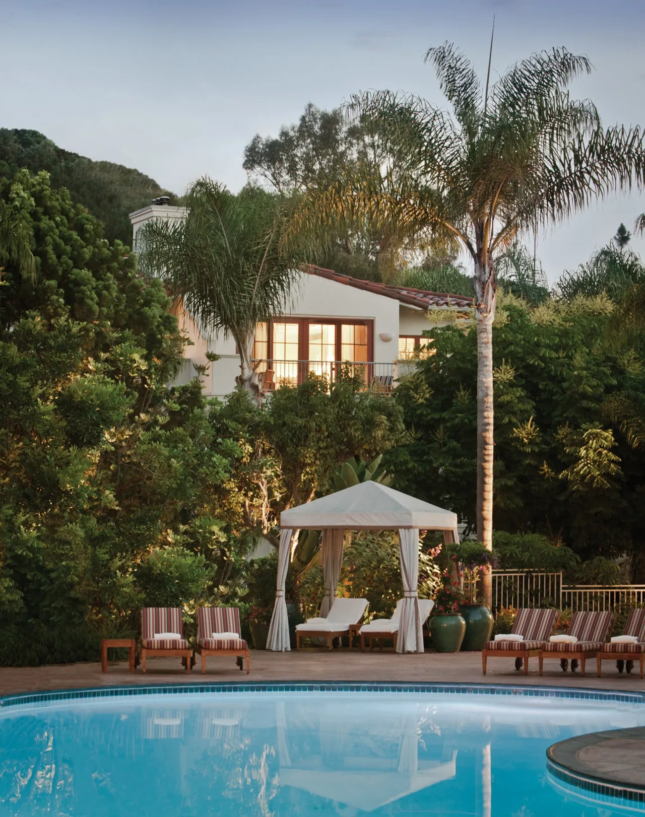 A cabana and comfortable lounge chairs line the swimming pool at Four Seasons San Diego.