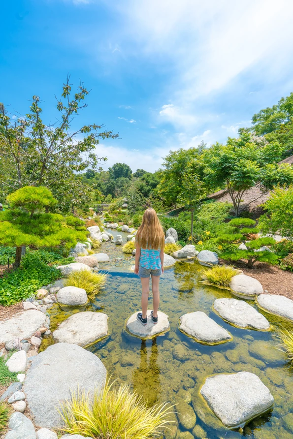 My daughter stands on a rock in the stream at JFG.