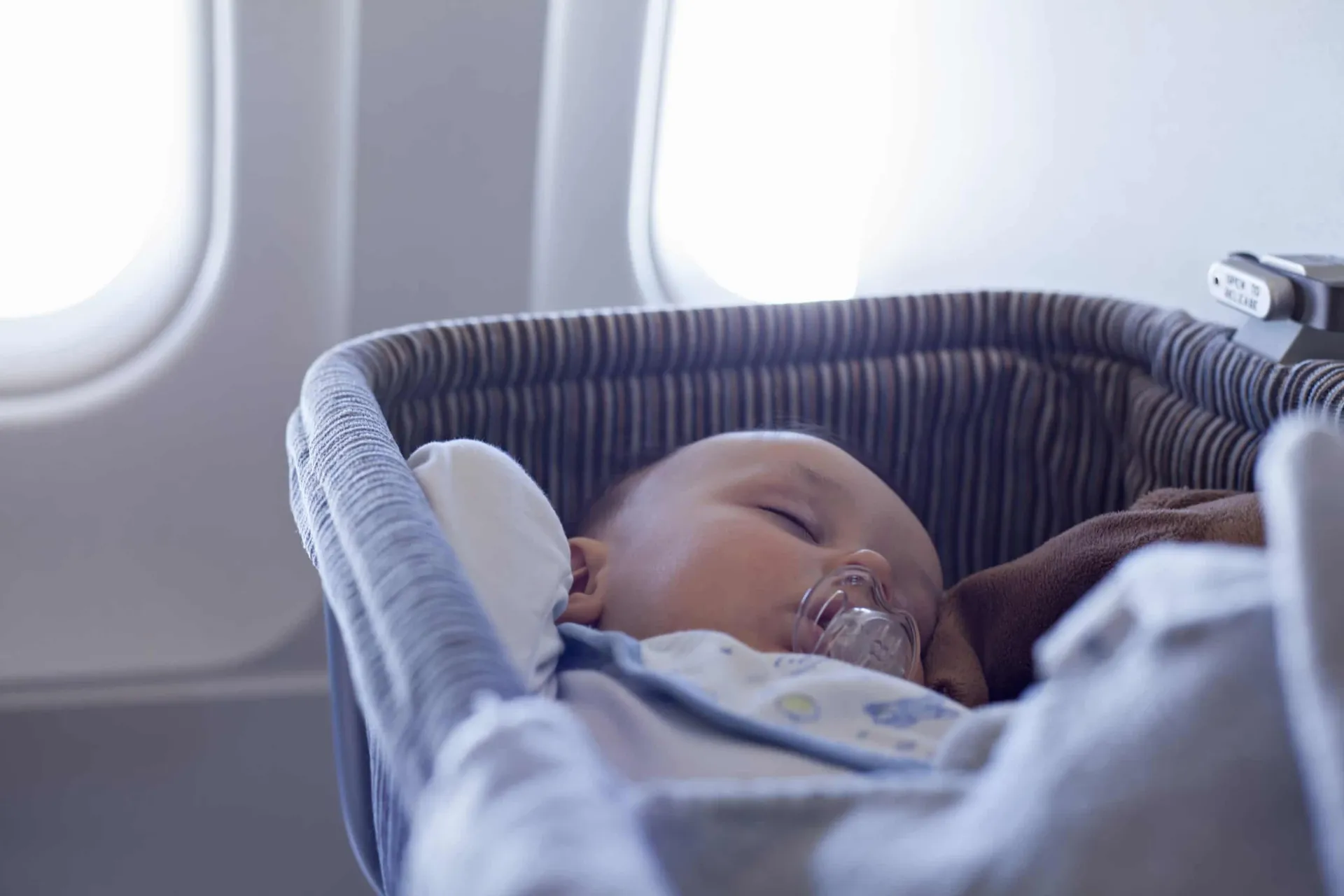 A baby sleeping in an airplane bassinet