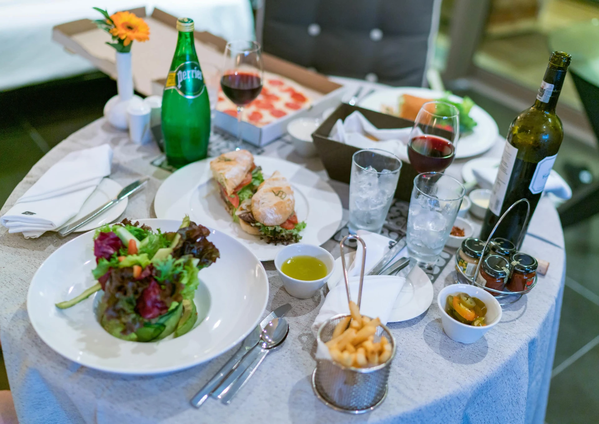 In-room dining tray with salad, sandwich, pizza and wine on top.