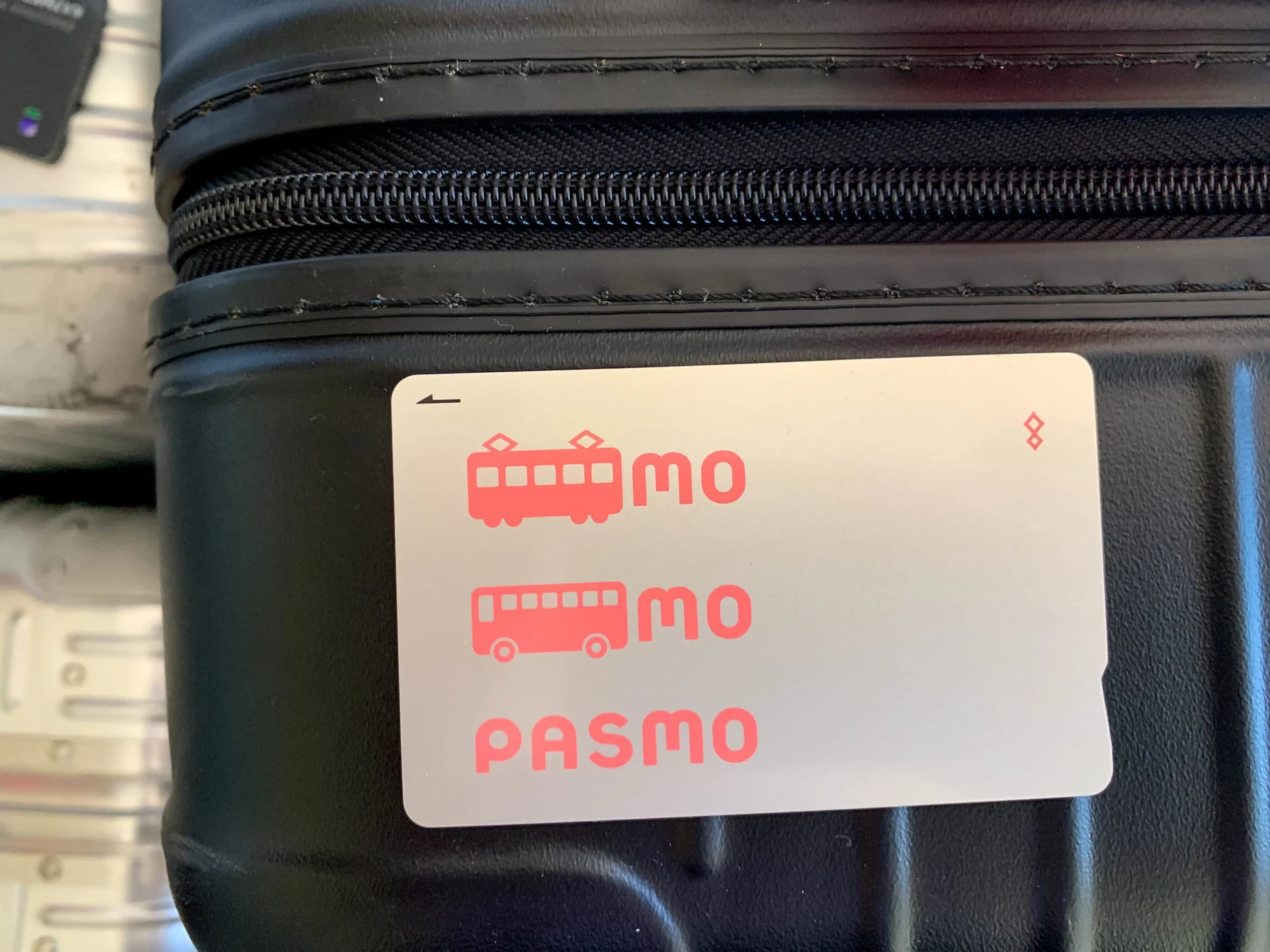 A Pasmo card sitting on top of a black suitcase