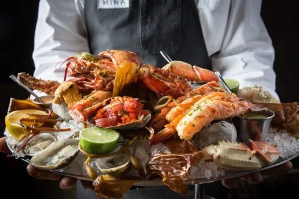 A server holds a shellfish platter from Bourbon Steak.