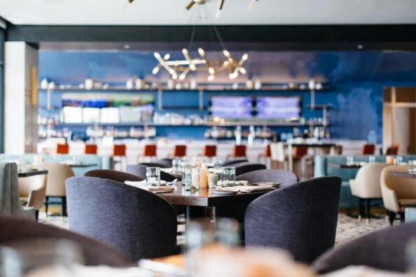 Interior shot of a set table with the cocktail bar in the background at AVEO restaurant inside Monarch Beach Resort.