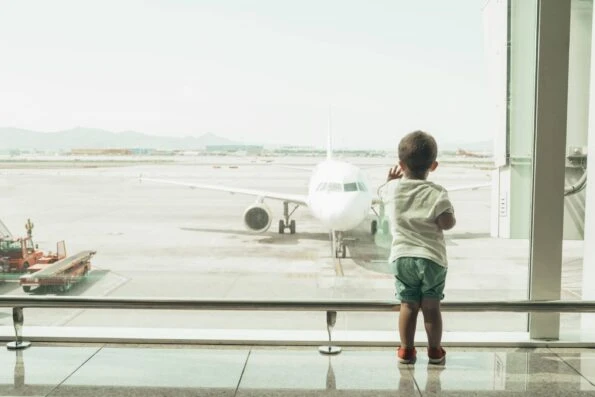 Boy at the airport looking at an airplane at the gate.