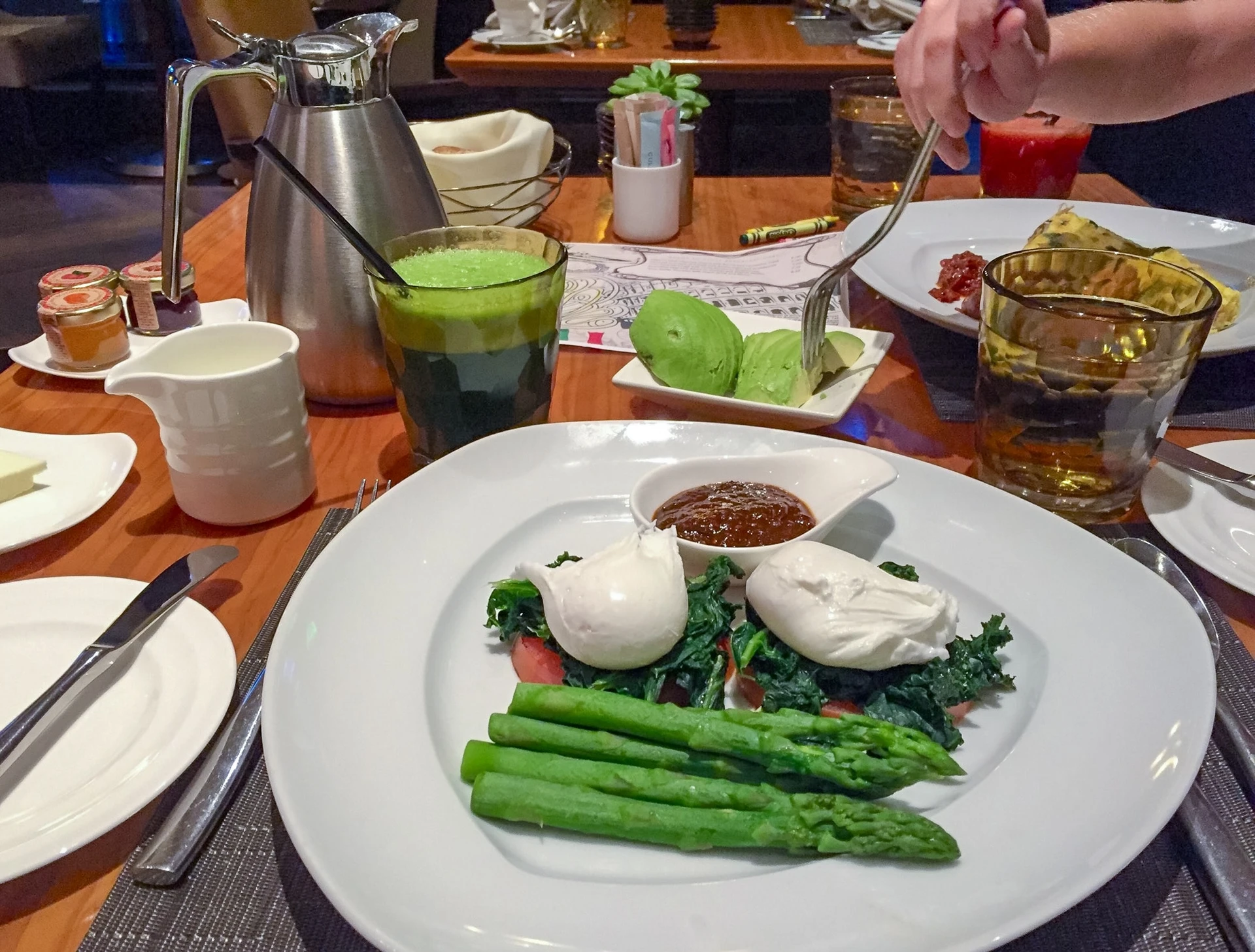 Poached eggs, steamed asparagus, and other vegetables on a plate at Culina as part of a healthy breakfast spread.