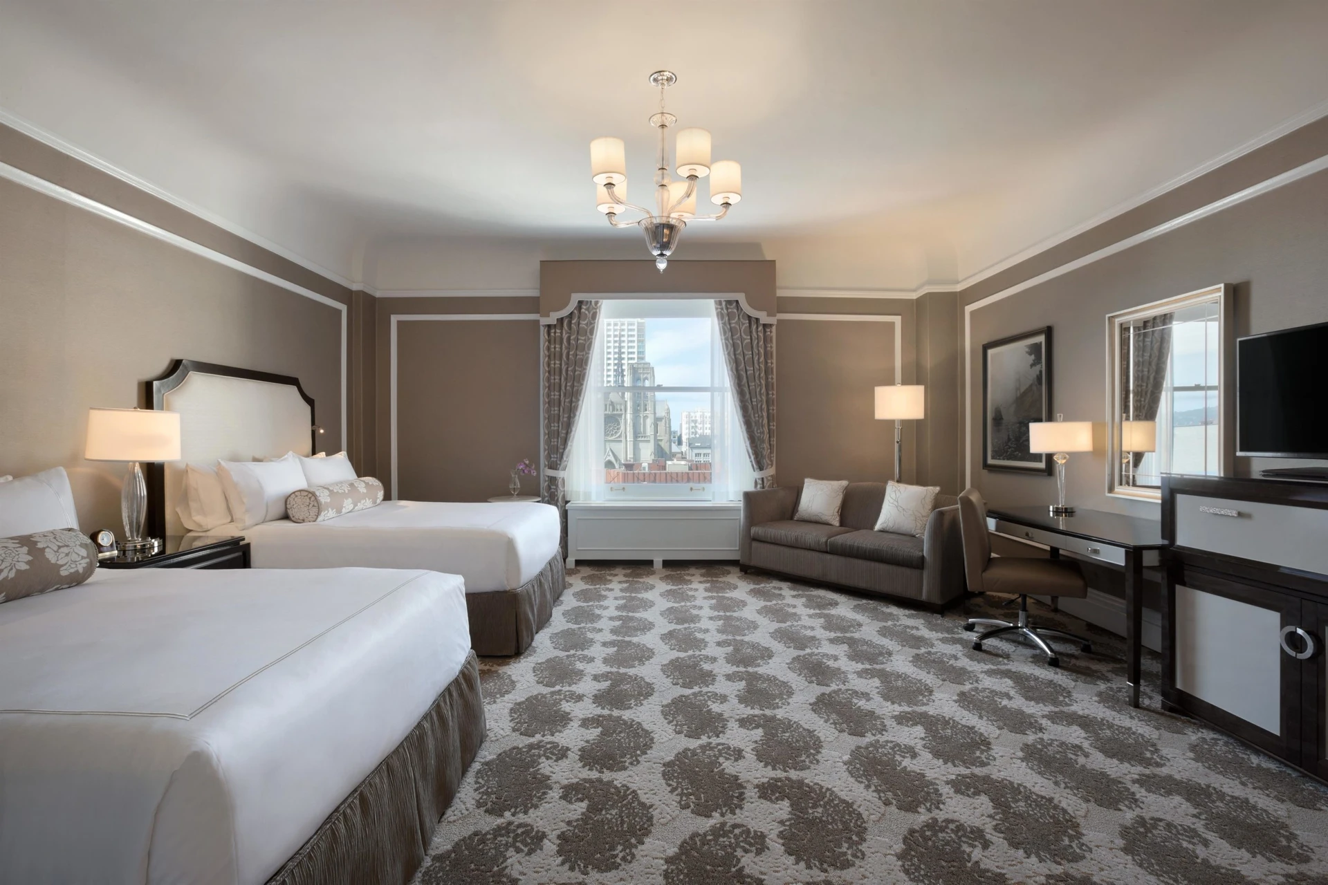 The interior of a Fairmont Queen/Queen room with taupe walls, dark woods and white accents.